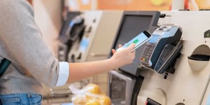 Woman is paying with smart phone at self-checkout