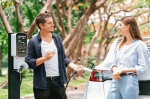 Man and woman charging electric car at outdoor charging station