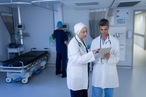 Doctors discussing patient information on a digital tablet in hospital