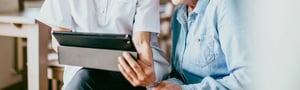 Healthcare professional showing information on a tablet to a patient