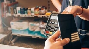 Customer making contactless payment with smartphone at POS terminal in store