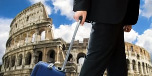 Business traveler with suitcase near Colosseum.
