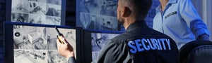 Security personnel monitoring surveillance footage on multiple screens