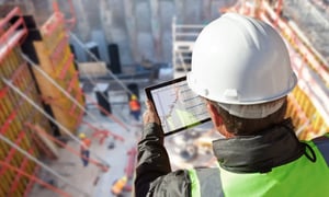 Construction worker using a tablet to review data at a building site.