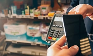 Customer making contactless payment with smartphone at POS terminal in store.