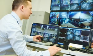 Security person monitoring multiple surveillance camera feeds.