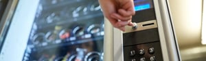 Hand pressing a button on a vending machine
